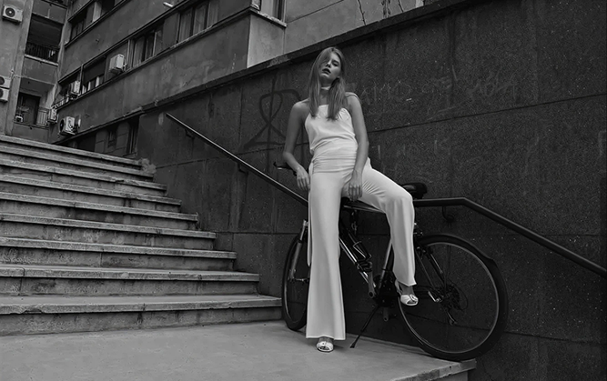 Woman sitting on a bicycle against a building with stairs